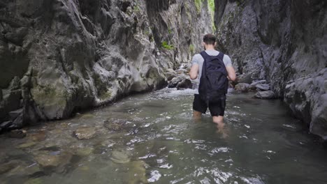 Young-man-walking-in-a-flowing-stream.-Inside-the-canyon.